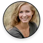 Portret van een lachende vrouw met blond haar in een natuurlijke veldomgeving, gekleed in een casual topje en met een ketting, vastgelegd bij zacht buitenlicht.